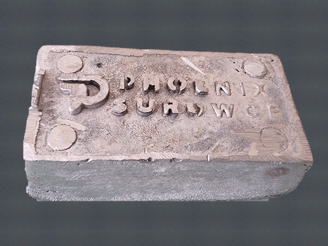 Aluminiowy wlewek z odlanym znakiem Phoenix Surowce — to zostaje z talerzy z danymi