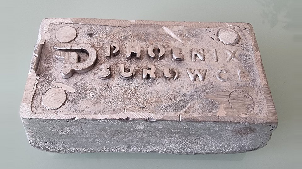 Aluminiowy wlewek z odlanym znakiem Phoenix Surowce